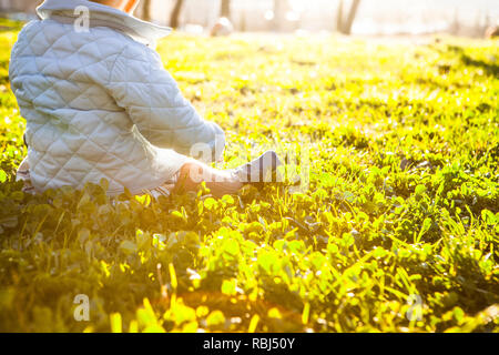 9 Monat Baby unter Sonnenstrahlen auf Gras Park. Vorteile des Sonnenlichts für Babys Konzept Stockfoto