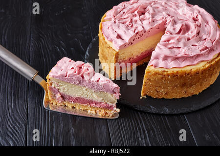 Himbeere layered Käsekuchen mit Frischkäse gefärbt mit Boden Himbeeren auf einen schwarzen Stein Fach auf hölzernen Tisch geschnitten überstieg, Ansicht von oben, Stockfoto