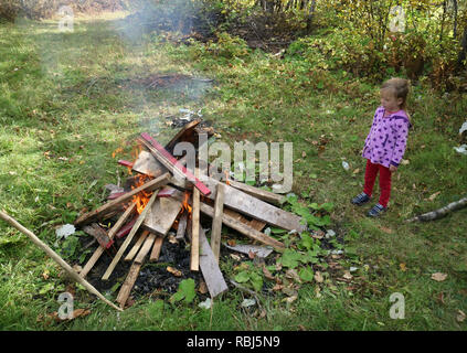 Ein kleines Mädchen (4 Jahre alt) an einem Lagerfeuer suchen Stockfoto