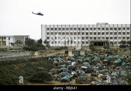 10. Oktober 1993 ein US-Armee Bell AH-1 Cobra Kampfhubschrauber patrouilliert niedrig über eine tented Flüchtlingslager vor der Polytechnischen Institut in Mogadischu, Somalia. Stockfoto