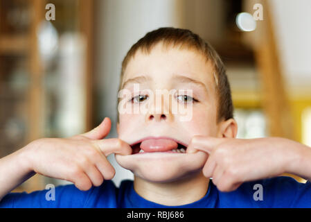 Ein Junge (6 Jahre alt) Gesichter ziehen an der Kamera Stockfoto