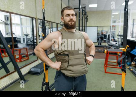 Portrait muskulös kaukasischen Bärtigen erwachsenen Mann in der Turnhalle, in kugelsicher gepanzert Weste gekleidet, Militär, Sport. Stockfoto