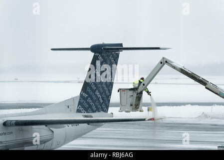 Ein Flughafen Mitarbeiter sprühen Heckscheibenheizung am Flügel eines Flugzeugs im Winter, das Flugzeug bereit für die Abreise. Die Stadt Quebec Jean Lesage Flughafen. Stockfoto