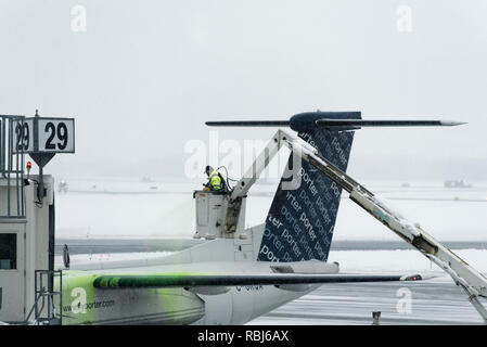 Ein Flughafen Mitarbeiter sprühen Heckscheibenheizung am Flügel eines Flugzeugs im Winter, das Flugzeug bereit für die Abreise. Die Stadt Quebec Jean Lesage Flughafen. Stockfoto