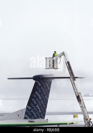 Ein Flughafen Mitarbeiter sprühen Heckscheibenheizung am Flügel eines Flugzeugs im Winter, das Flugzeug bereit für die Abreise. Die Stadt Quebec Jean Lesage Flughafen. Stockfoto