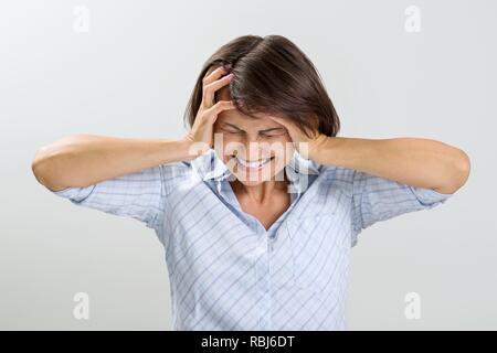 Portrait von enttäuscht, Frau, geschlossen, Augen und Ohren, schreiend in Verzweiflung, Bild von Haus auf einem hellen Hintergrund. Mimik, Reaktion und ne Stockfoto