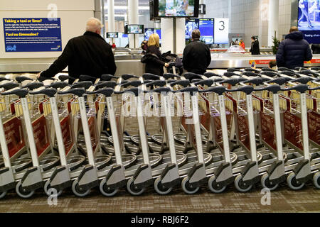 Menschen, die durch die Reihen der Gepäckwagen in Toronto Pearson Flughafen warten auf Ihrem Gepäck ankommen. Stockfoto