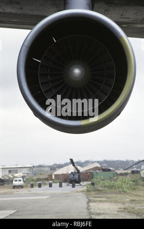 10. Oktober 1993 einer der vier großen Motoren von der USAF Lockheed Galaxy C5 Military Transport Jet der Air Mobility Command, auf dem Flughafen von Mogadischu in Somalia geparkt. Im Hintergrund ist ein Bell UH-1 Iroquois (Huey) Hubschrauber. Stockfoto