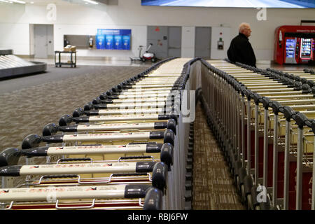 Menschen, die durch die Reihen der Gepäckwagen in Toronto Pearson Flughafen warten auf Ihrem Gepäck ankommen. Stockfoto