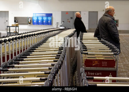 Menschen, die durch die Reihen der Gepäckwagen in Toronto Pearson Flughafen warten auf Ihrem Gepäck ankommen. Stockfoto