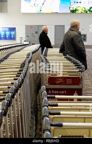 Menschen, die durch die Reihen der Gepäckwagen in Toronto Pearson Flughafen warten auf Ihrem Gepäck ankommen. Stockfoto