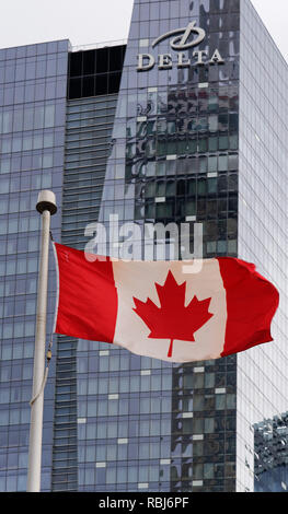 Der CN Tower, spiegelt sich in dem Hotel Delta Gebäude in Toronto, mit der Kanadischen Flagge vor Stockfoto