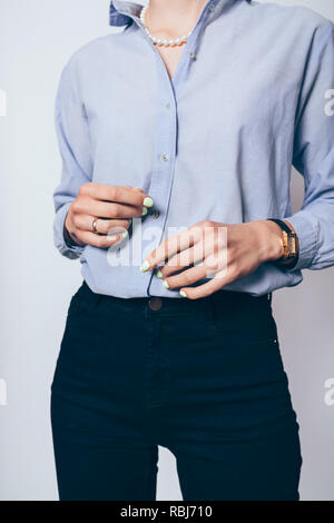 Elegante junge geschäftsfrau mit schwarzen Röhrenjeans, blaues Hemd und Perlenkette, close-up. Stockfoto