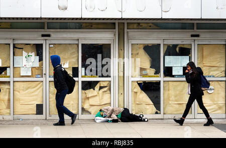 Eine obdachlose Person schlafen auf dem Gehsteig vor einem geschlossenen Geschäft, Leute, Spaziergang durch in Toronto, Kanada Stockfoto