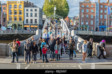 Menschen gehen über die Ha'Penny Bridge über den Fluss Liffey in Dublin, Irland. Stockfoto