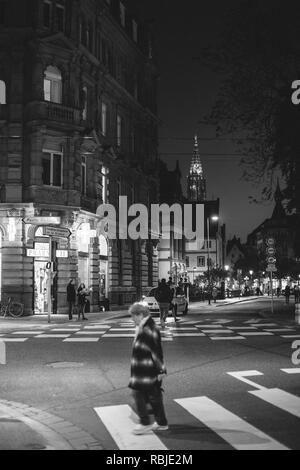 Straßburg, Frankreich - 31.Oktober 2017: Fußgänger nachts auf die Straßburger Straße mit der Kathedrale Notre-Dame im Hintergrund - ältere Frau Kreuzung Straße Stockfoto