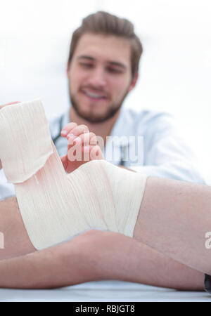 Arzt bandagieren eine Wunde am Bein des Patienten Stockfoto