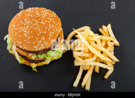 Saftige doppelten Cheeseburger mit Rindfleisch, Cheddar und Salat und Pommes frites auf schwarzem Hintergrund. Ansicht von oben Stockfoto