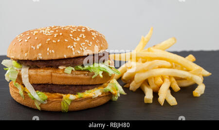 In der Nähe Bild von einem leckeren double Cheeseburger mit Rindfleisch, Cheddar, Salat in einem sesambrötchen Stockfoto