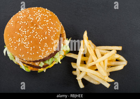 Saftige doppelten Cheeseburger mit Rindfleisch, Cheddar und Salat und Pommes frites auf schwarzem Hintergrund. Ansicht von oben Stockfoto