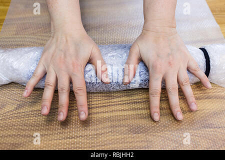 Werkstatt von Hand eine Fleece Handschuhe von blau Merino Schafschurwolle nass Filzen Prozess - Handwerker rollt eine Matte mit gefilzte Handschuhe für Walken Stockfoto