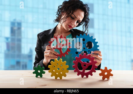 Geschäftsfrau versucht Gänge Stücke zu verbinden. Konzept der Teamarbeit, Partnerschaft und Integration Stockfoto