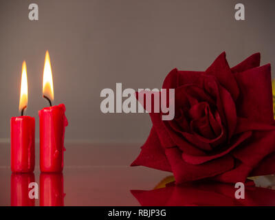 Konzept der Liebe rote Kerzen und eine rote Rose mit einem warmen Hintergrund Stockfoto