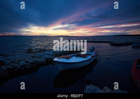 Schönen Sommer Marine bei Sonnenuntergang. Kleine Boote im Meer Einlass verankert Ruhe Flachwasser durch rote Sonne Strahlen der untergehenden Sonne beleuchtet. Tourismus, Angeln, Tauchen Stockfoto