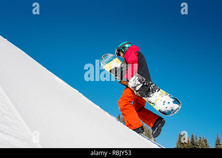 Volle Länge Schuß eines voll ausgestatteten Snowboarder, Freerider zu Fuss den Hang hinauf, seinem snowboard Durchführung an einem sonnigen Tag in den Bergen copyspace Natur Winter Sport Active Lifestyle Konzept. Stockfoto