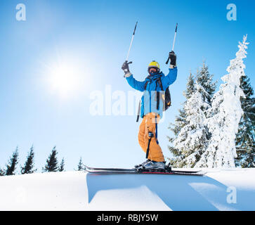 Professionelle freeride Skier, Skistöcke seine Arme in die Luft auf der Spitze des Berges leistung Führung Feier gewinnen Glück Positivität Gestik reiten Lifestyle Extrem. Stockfoto