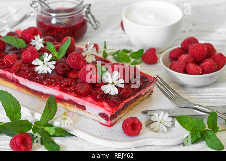 Himbeere Kuchen mit frischen Beeren und Minze mit Blumen auf weißem Holz- Tabelle eingerichtet. süßes Dessert zum Frühstück. Nach oben Schließen Stockfoto
