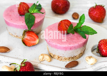 Vegan raw strawberry Cheesecake mit frischen Beeren, Minze und Muttern. Gesunde vegane Ernährung Konzept Stockfoto
