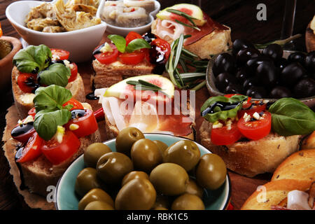 Italienische Antipasti Wein Snacks. Käsesorte, mediterrane Oliven, Gurken, Prosciutto di Parma, Tomaten, Artischocken und Wein in Gläsern auf Registerkarte Stockfoto