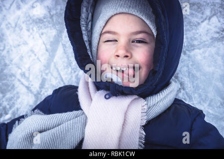Winter fröhliches Kind Portrait auf Schnee eis Hintergrund Spaß auf verschneiten Eisbahn im Winter Urlaub Stockfoto