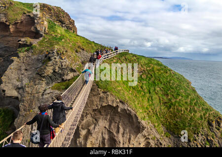 Touristen und Besucher erkunden und über die Hängebrücke zu Fuß bei Carrick-a-Rede und Larrybane Bay an der Westküste Irlands. Stockfoto