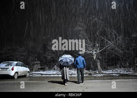 Kaschmir Bewohner gesehen zu Fuß durch eine Straße bei Schneefall in Srinagar, Indien verwalteten Kaschmir. Schneefall peitschten die meisten Teile des Kaschmir Valley am Abend als minimale Temperaturen über den Gefrierpunkt stieg. "Nassen Wetterbedingungen von leichter bis mäßiger Schneefall und Regen gekennzeichnet sind wahrscheinlich bis Januar 14, ein Wetter offizielle durchsetzen, sagte. Stockfoto