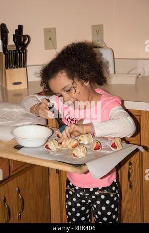 Vadnais Heights, Minnesota. Fünf Jahre alte rassische Bi - Kind helfen, gesunde Apple machen behandelt im Ofen backen. Stockfoto