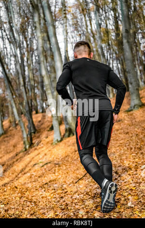 Athleten, die im Wald, Herbst, braune Blätter, arbeiten härter und härter. Stockfoto