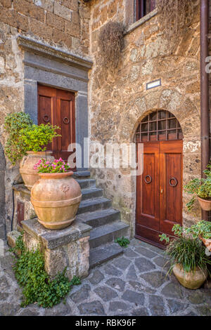 Foto eines romantischen, privaten Innenhof mit der Toskana. Blumen sind aus Lehm Vasen mit weatered Holz mittelalterlichen Türen. Stockfoto