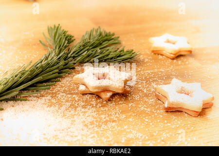 Weihnachten Plätzchen mit Puderzucker und Kristallzucker auf hölzernen Tisch neben Tanne Zweig Stockfoto