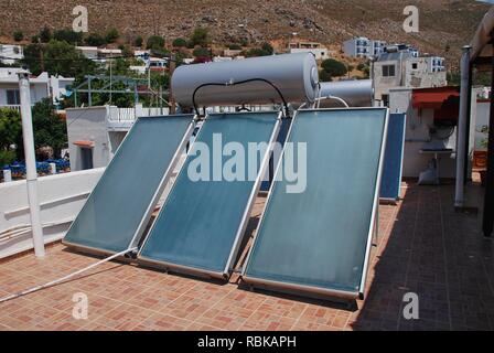 Eine Bank mit Solarheizung Sonnenkollektoren auf dem Dach in Livadia auf der griechischen Insel Tilos am 21. Juni 2018. Stockfoto