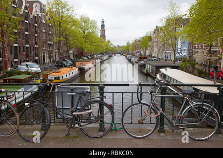 Fahrräder, die auf einer Brücke über einen Kanal in Amsterdam geparkt Stockfoto