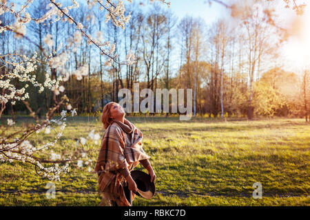 Gerne Frau mittleren Alters entspannen im Frühjahr blühenden Garten bei Sonnenuntergang. Ältere Frau zu Fuß in das Feld ein. Lady das Leben zu genießen und Spaß haben Stockfoto