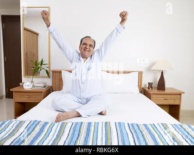 Alter Mann STRECHING seine Arme, ALS ER AM MORGEN AUFWACHTE Stockfoto
