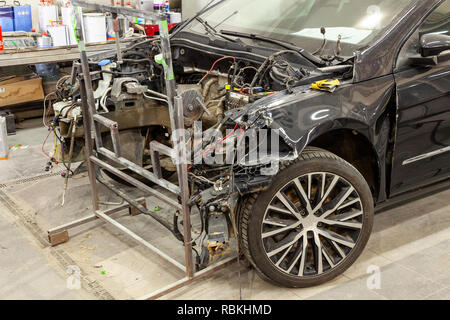 Das schwarze Auto nach einem schweren Unfall mit einem vollständig gebrochen vor dem Körper ohne Motor mit Glasscherben, wartet auf die Reparatur in einem wor Stockfoto