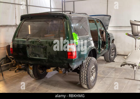 Die Green Car nach einem schweren Unfall mit einem vollständig gebrochen vor dem Körper ohne Motor mit Glasscherben, wartet auf die Reparatur in einem wor Stockfoto