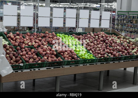 Ein großes Regal mit Körben mit verschiedenen Arten von Äpfeln im Obst Abteilung der Shopping Center. Frische und gesunde Lebensmittel für die Ernährung auf eine Dai Stockfoto