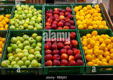 Ein großes Regal mit Körben mit verschiedenen Arten von Äpfel und Zitronen im Obst Abteilung der Shopping Center. Frische und gesunde Lebensmittel für alle Stockfoto