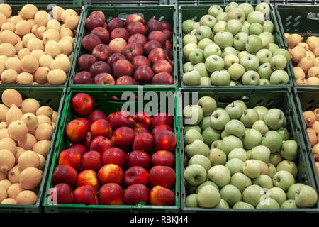 Ein großes Regal mit Körben mit verschiedenen Arten von Äpfeln im Obst Abteilung der Shopping Center. Frische und gesunde Lebensmittel für die Ernährung auf eine Dai Stockfoto