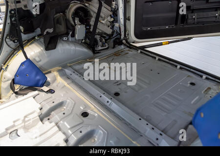 Die Rückseite des Autos auf der Rückseite eines SUV ohne Haut, für die Reparatur und die Leistung der Schallschutz in einem Auto Tuning Workshop vorbereitet. Stockfoto